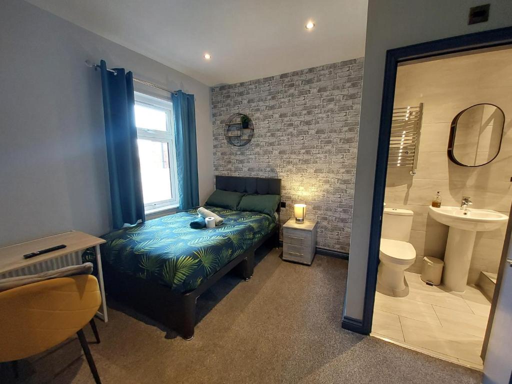 a bedroom with a bed and a bathroom with a sink at Tudor Road House in Leicester