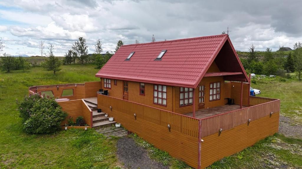 a large wooden house with a red roof at Secret lagoon cabin in Fludir