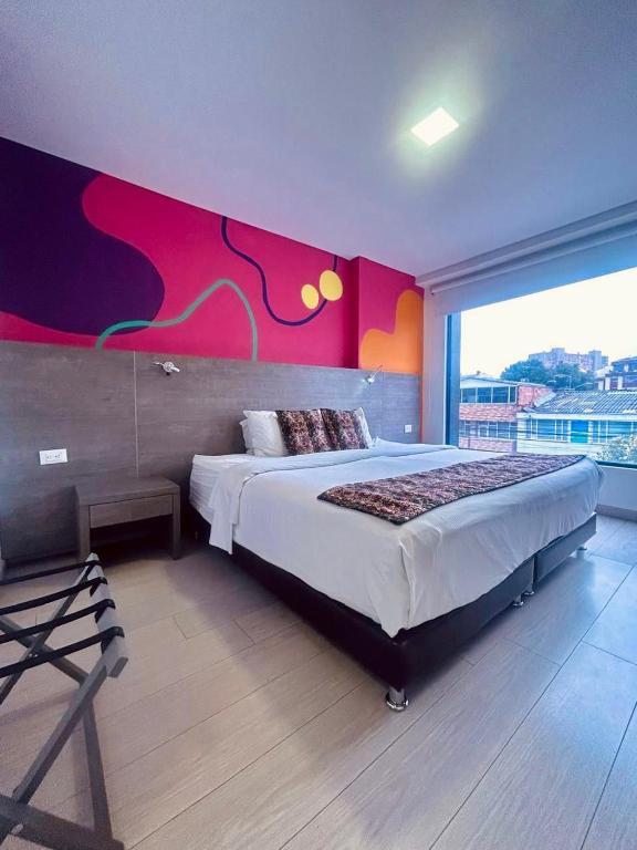 a bedroom with a large bed with a colorful wall at Agora Suites Hotel, Check-in digital fácil con atención virtual 24h in Bogotá