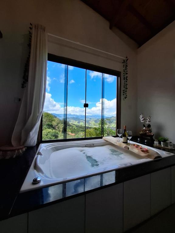 a large bath tub in a bathroom with a large window at Pousada Vitoria in Gonçalves