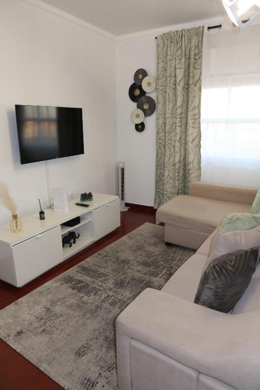 a living room with a white couch and a tv at Apart Lisbon Airport in Lisbon
