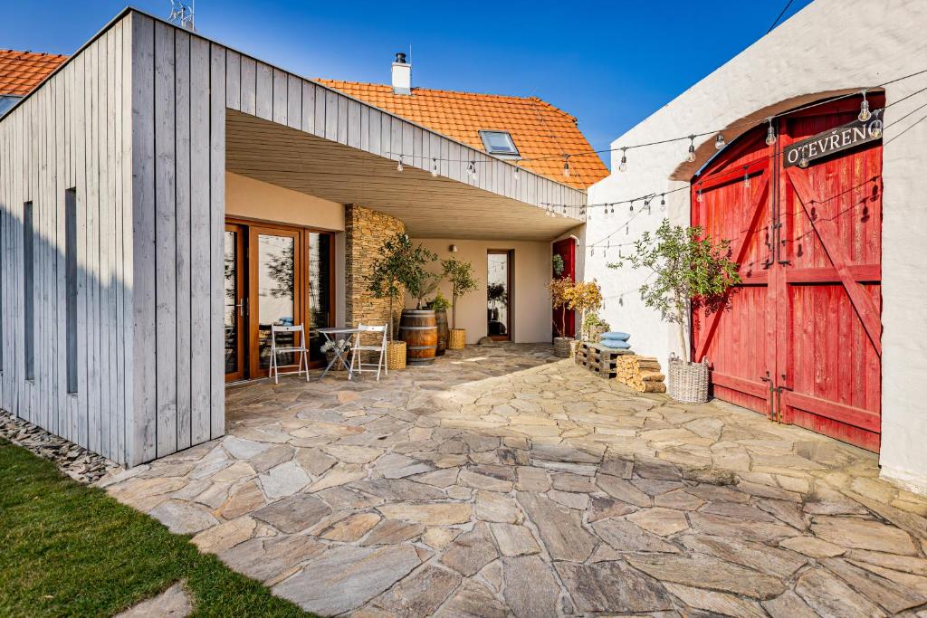 a barn with a red door and a patio at Penzion U Kapličky in Znojmo