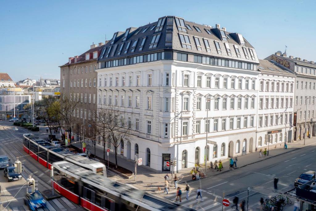a large white building on a city street with a bus at Hotel Alser in Vienna