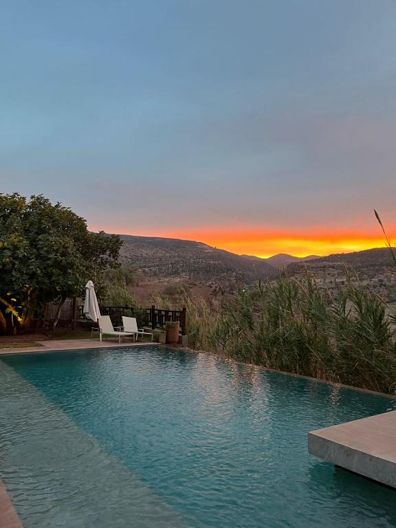a swimming pool with a sunset in the background at Le Figuier du Lac Bin elouidane in Bine el Ouidane