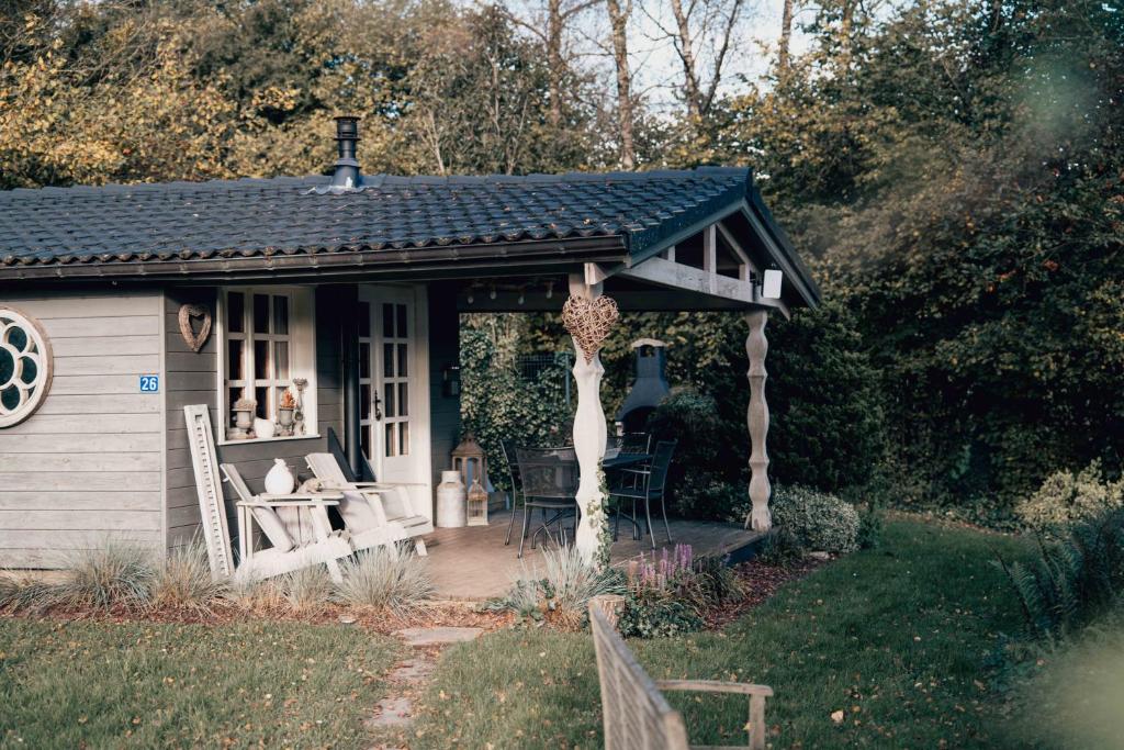 a small house with a porch with chairs and a table at Chalet d'hôtes - Les Daims - Petit déjeuner inclus in Fauvillers