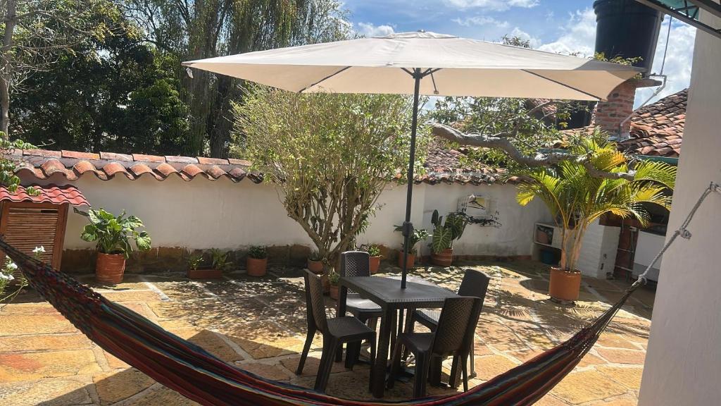 a hammock with a table and chairs and an umbrella at Casa Garaje in Barichara