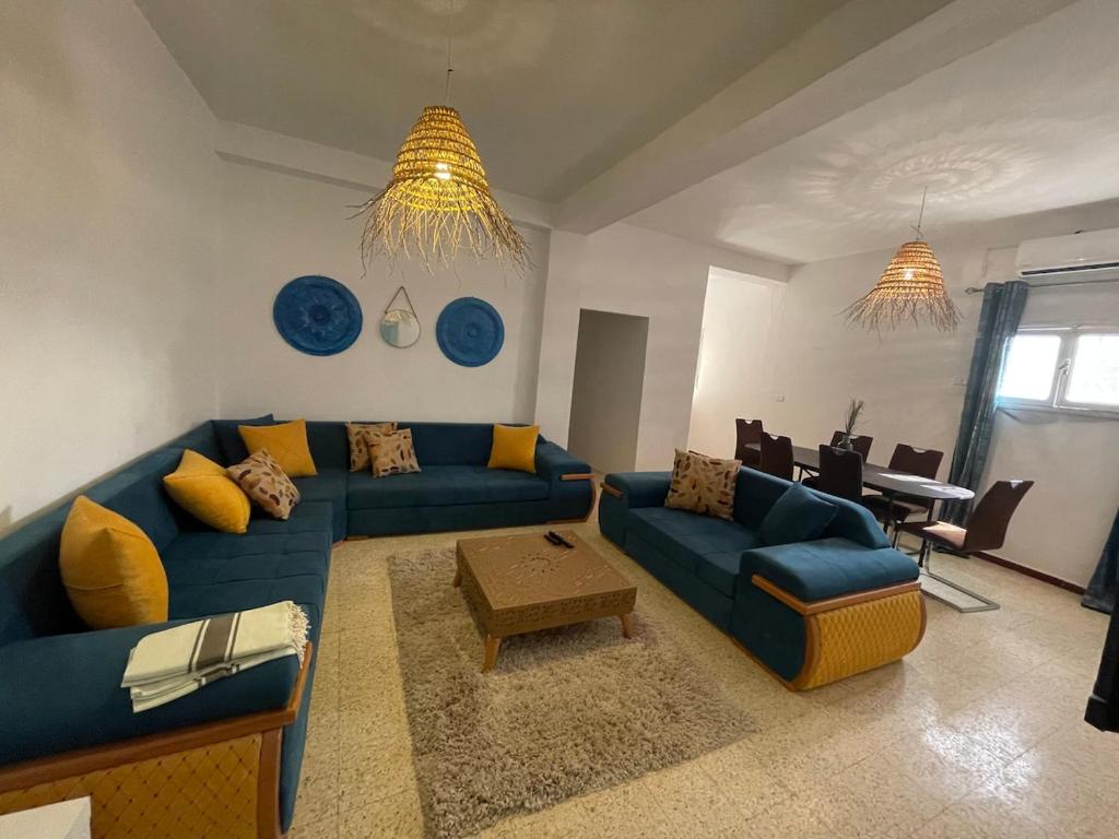a living room with a blue couch and a table at Aghir DJERBA Erdgeschosswohnung in Al Ḩaddādah
