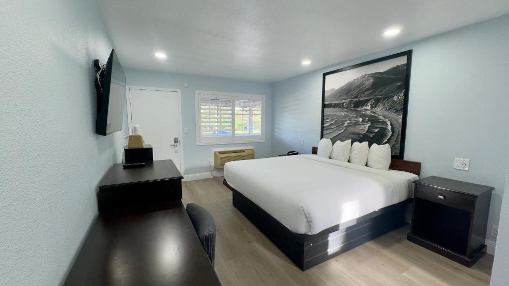 a hotel room with a white bed and a desk at Pelican Inn in Monterey