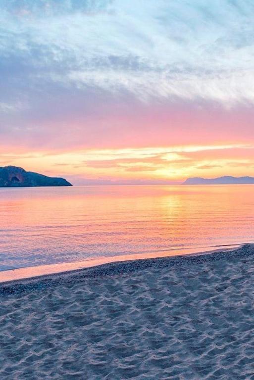a beach with a sunset in the background at Nadra Beachfront Suites in Platanias
