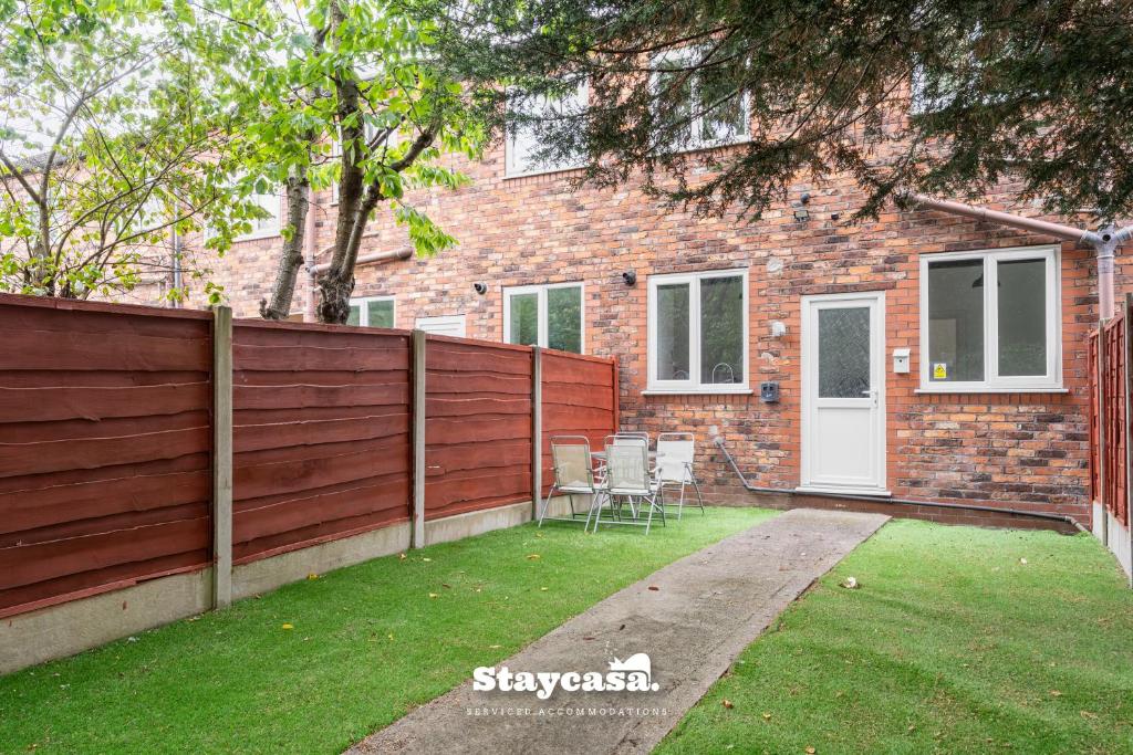 a house with a fence and chairs in the yard at Spacious 2BR Home w Garden 2-Min Walk to Town in Stockport