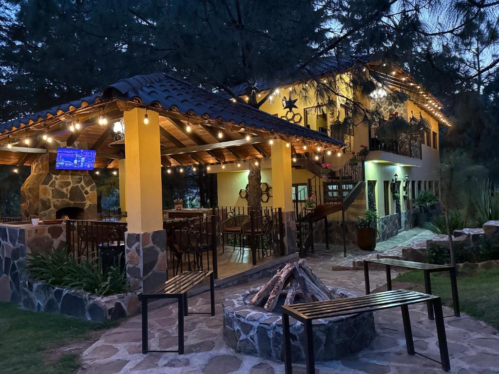 a pergola with benches and a grill in front of a building at Hermosa cabaña con terraza para disfrutar Cabañas puerta del bosque Mazamitla in Mazamitla