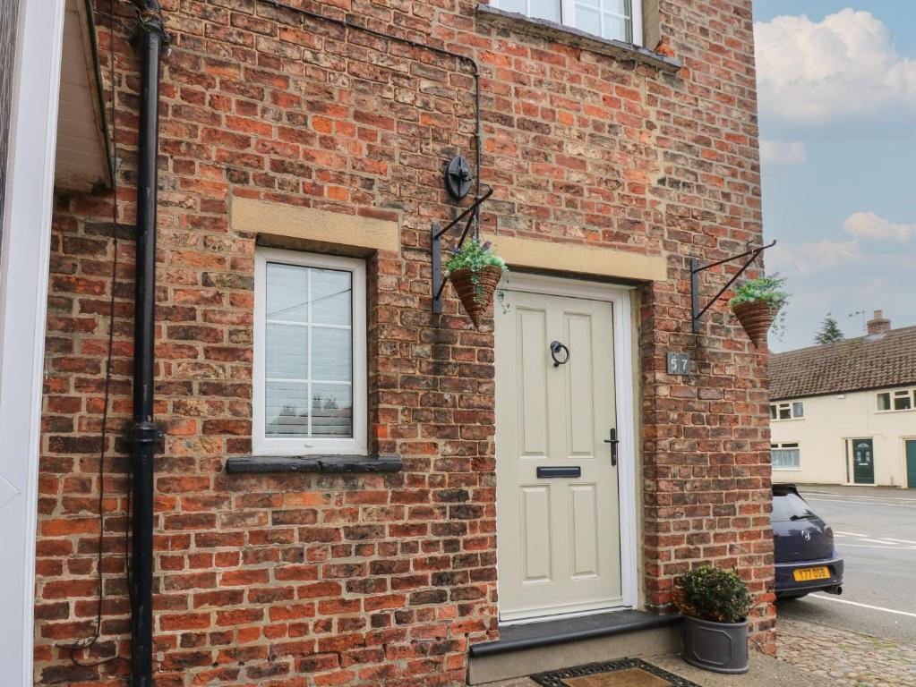 a brick house with a white door and two windows at 57 Cockpit Hill in Northallerton