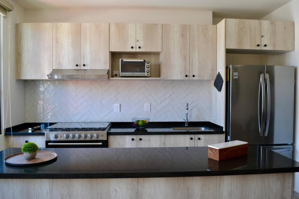 a kitchen with a stainless steel refrigerator and black counter top at Encanto Department We Bill in Alcocer