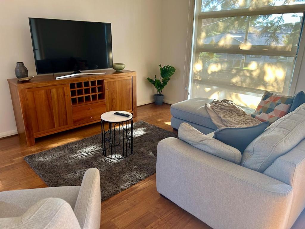 a living room with a couch and a flat screen tv at Modern Gem Steps from Everything You Need in Croydon North