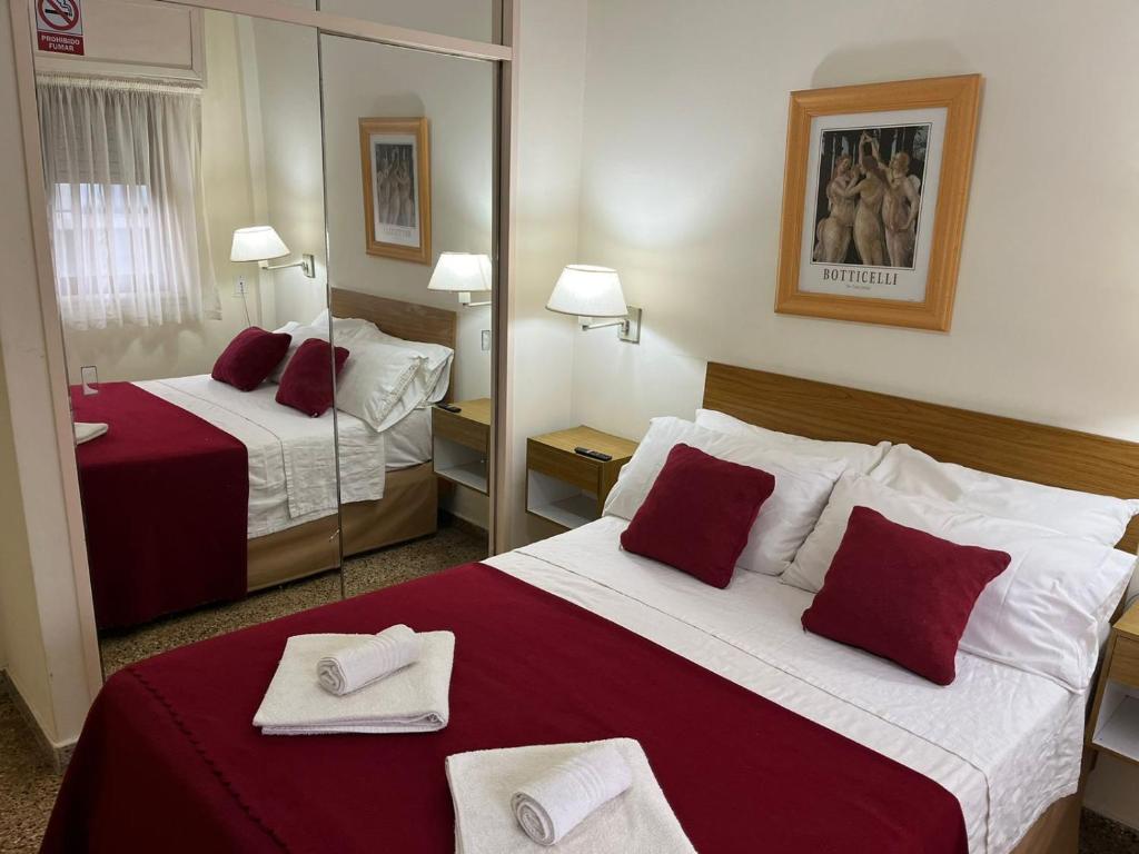 a hotel room with two beds and a mirror at Hotel Carmen in San Bernardo