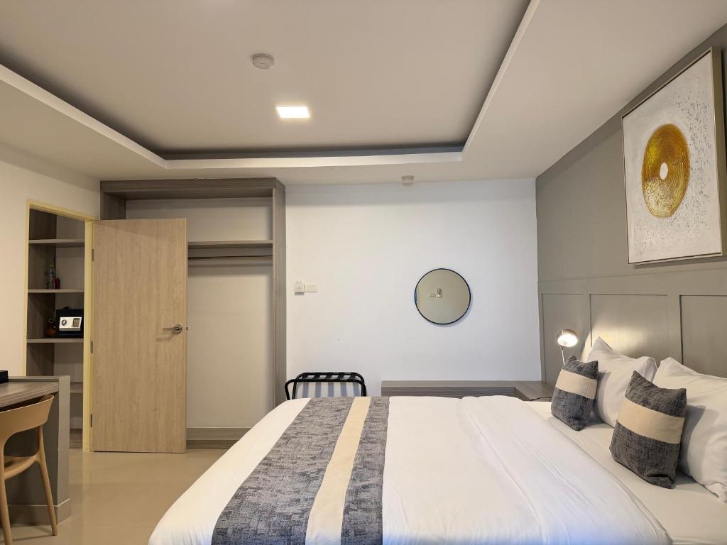 A made bed sits beside an open wardrobe and a small vanity or desk area.
