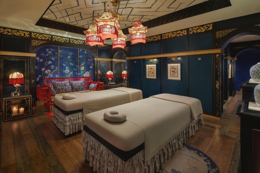 a bedroom with two beds in a room with blue walls at Capella Hanoi in Hanoi