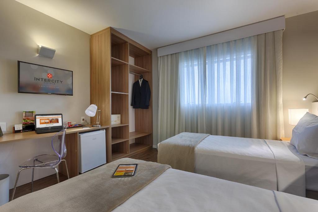 um quarto de hotel com duas camas e uma janela em Intercity BH Expo em Belo Horizonte