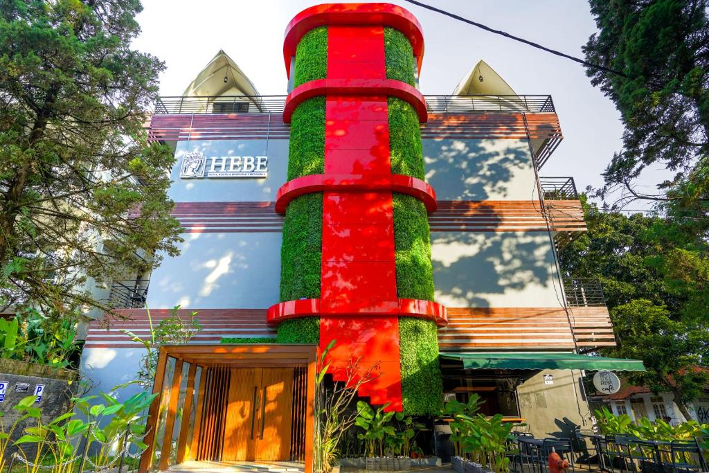 a building with a red and green pole in front of it at Hebe Hotel, Hostel & Hospitality Network in Sawah