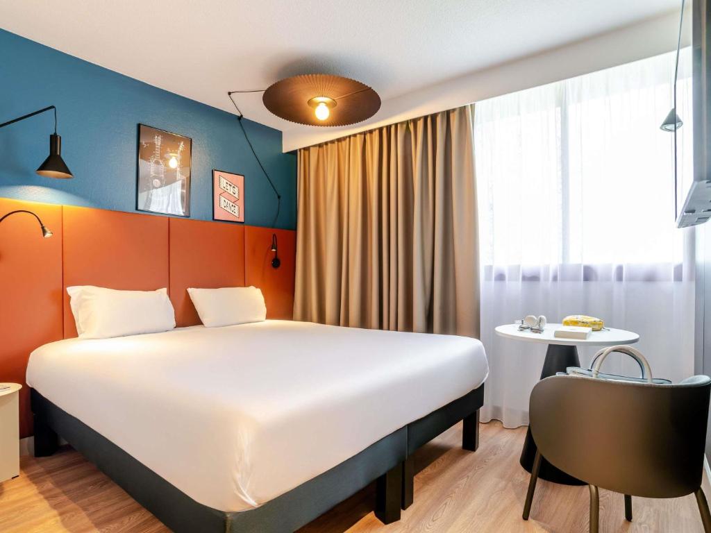 a hotel room with a large bed and a table at ibis Bordeaux Saint Emilion in Saint-Émilion