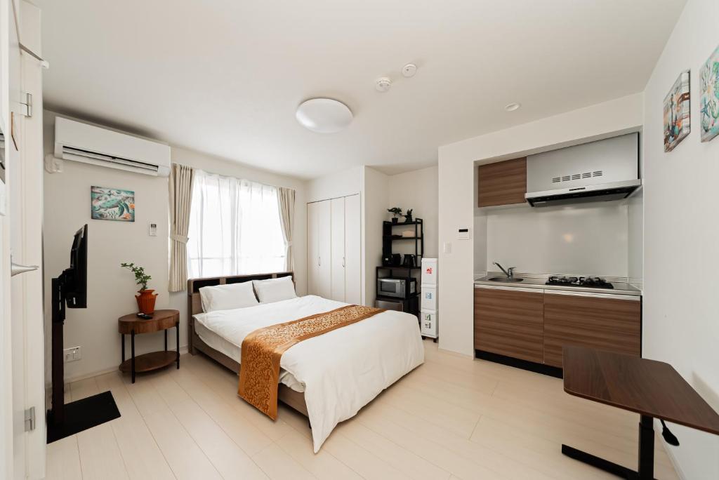 a bedroom with a white bed and a kitchen at SAIEI Hotel 东京小岩 JR京成双站直达成田羽田迪士尼适合家庭团队整栋多房型 in Tokyo