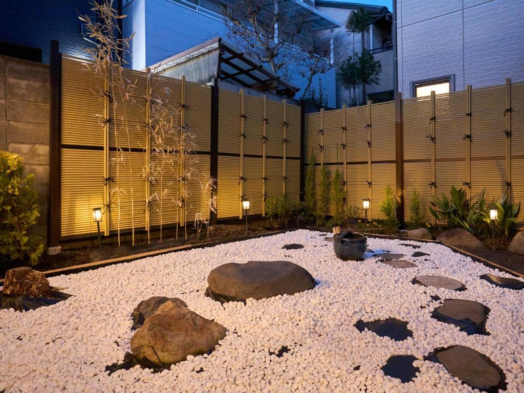 a garden with rocks on the ground in front of a fence at Villa near Kinkakuji Pets OK free Parking 金閣寺周辺 貸切町屋 ペットOK 無料駐車場 in Kinugasa