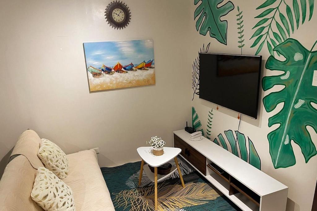a living room with a couch and a flat screen tv at Tropical Themed 2 Bedroom Condo in Mandaue City
