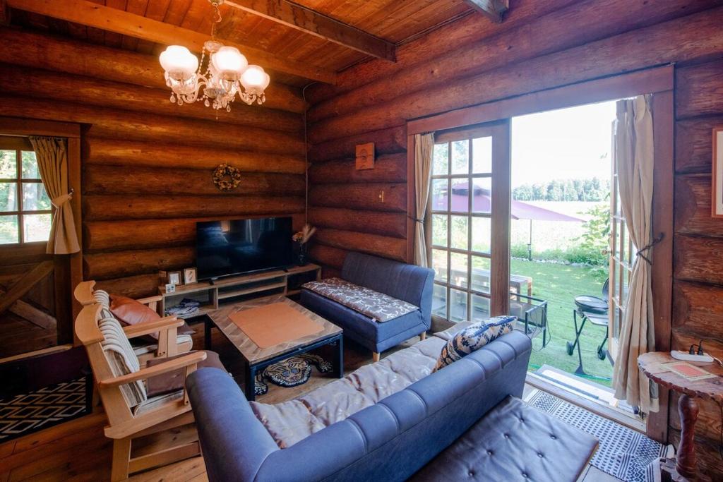 a living room with a couch and a television in a log cabin at Forest Villa Rio Biwako in Takashima
