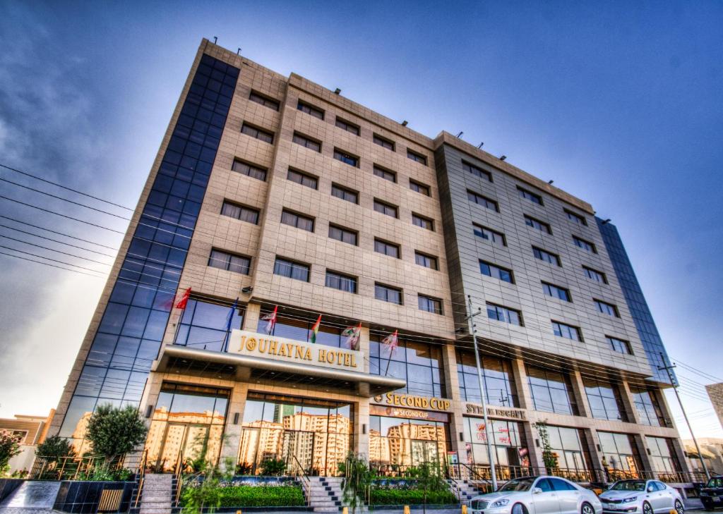 un grand bâtiment avec des voitures garées devant lui dans l'établissement Jouhayna Hotel&Suite, à Erbil
