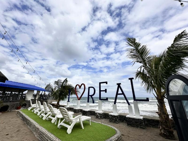 a row of white chairs in front of the ocean at Appleton Little Paradise Beach Resort & Restaurant REAL QUEZON in Real