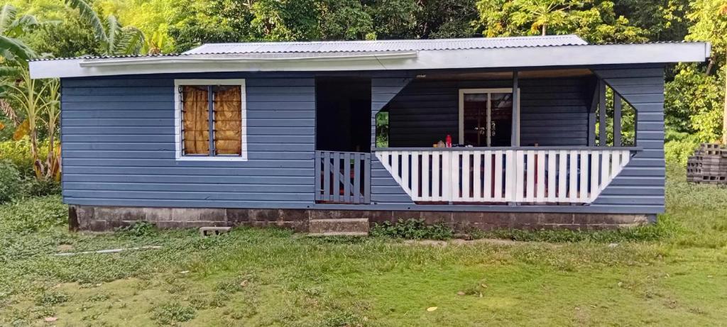 a blue tiny house with a porch in a yard at Knox's Beachfront Homestay in Nalauwaki