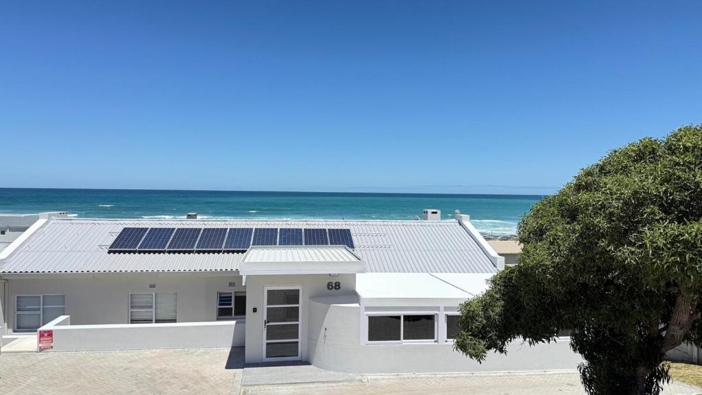 a white house with solar panels on the beach at Blue-breaker view in Struisbaai