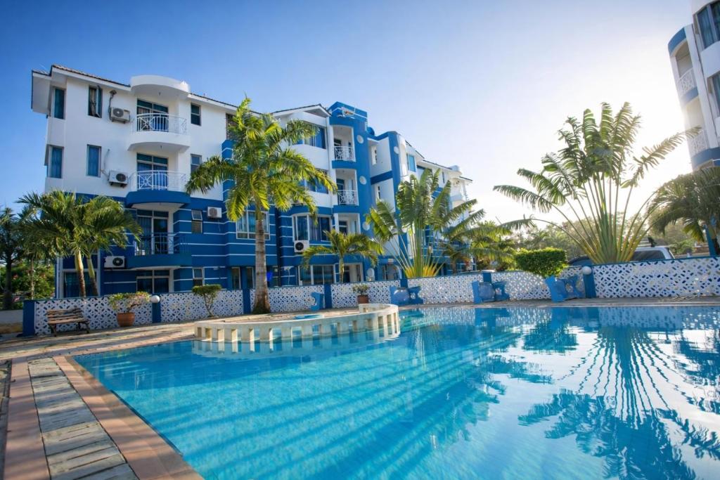 a swimming pool in front of a building at Ary Homestay Nyali At Shikara Apartments 5th Avenue Nyali, Mombasa, Kenya in Mombasa