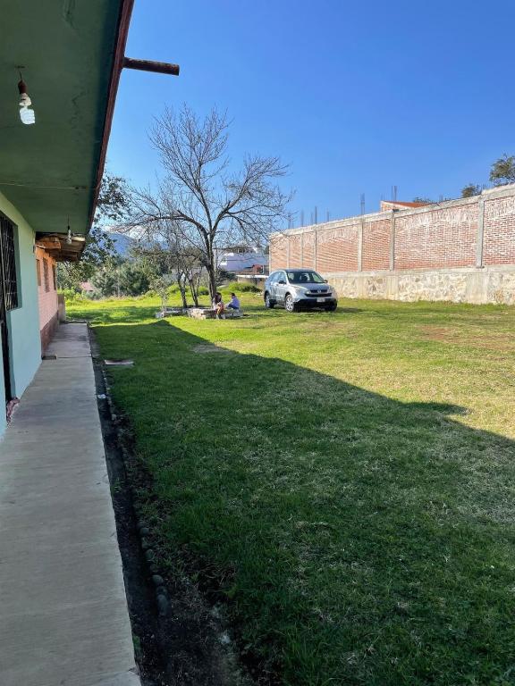 a grassy yard with a car parked next to a wall at Casa de campo en Zacatlán in Zacatlán