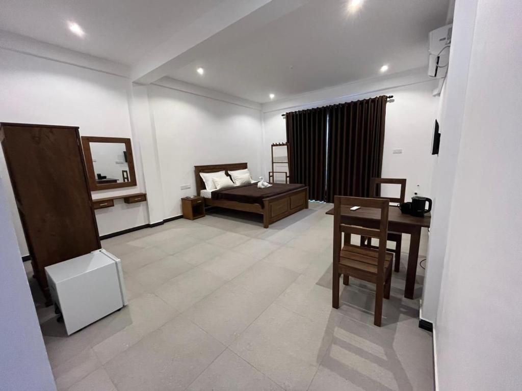 a room with a bed and a table and a desk at AB Villa in Hikkaduwa