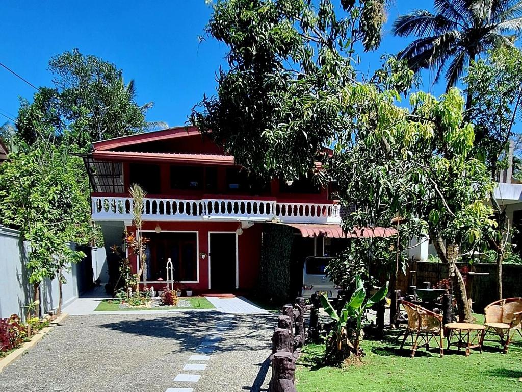 a red and white house with chairs and trees at Badulla Bliss in Badulla