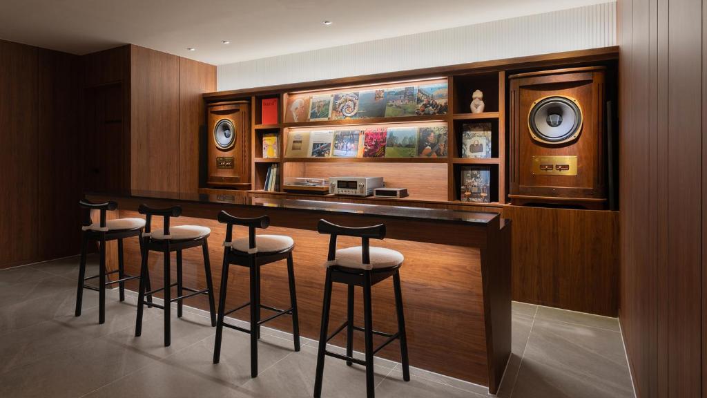 a bar with four stools in a room at Maison The Denbasta Hotel in Busan