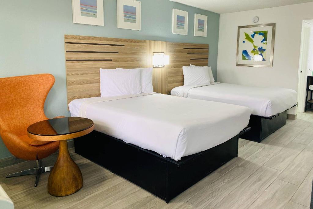 a hotel room with two beds and a chair at Rodeway Inn Clearwater - Central in Clearwater