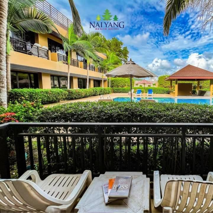 a patio with a table and chairs next to a hotel at Naiyang Beach Hotel SHA Plus in Nai Yang Beach