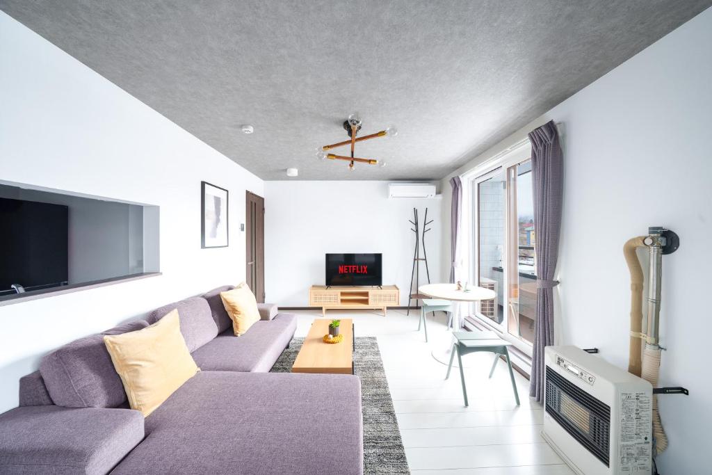 a living room with a purple couch and a tv at Hills Niseko 206 in Wada
