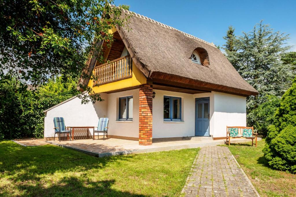 a cottage with a thatched roof and two chairs at Reethaus im Ostseebad Trassenheide in Trassenheide