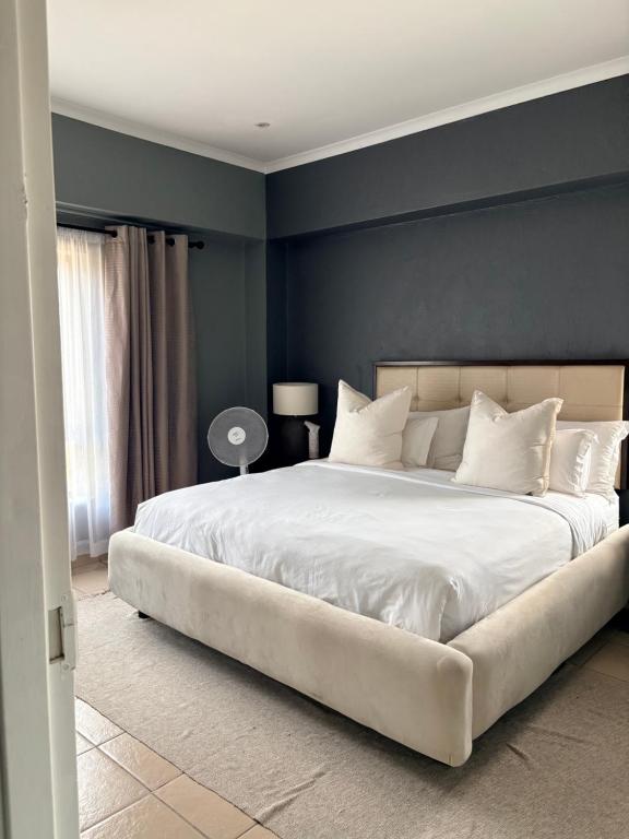 a bedroom with a large white bed with blue walls at Tranquil Arcade in Boschrand
