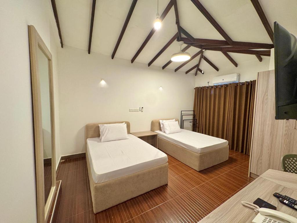 a room with two beds and a tv in it at The Dimora Residence in Kurunegala