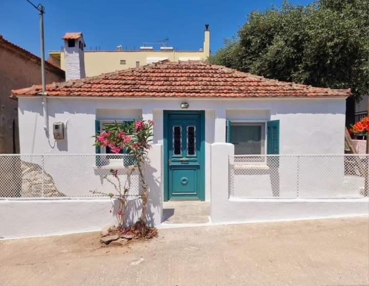 a small white house with a green door at Traditional mama house in Skala Sotiros