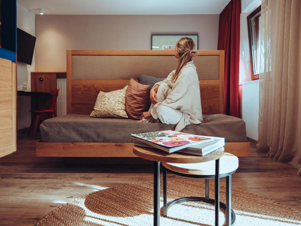 a woman sitting on a couch in a living room at Hotel Schönberg in Rio Bianco