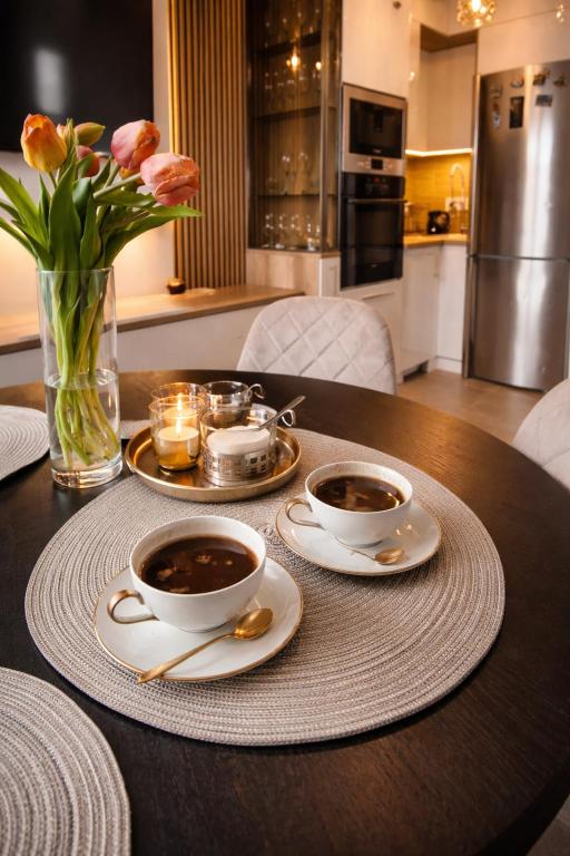 two cups of coffee sitting on a table with flowers at Garden lux in Belgrade