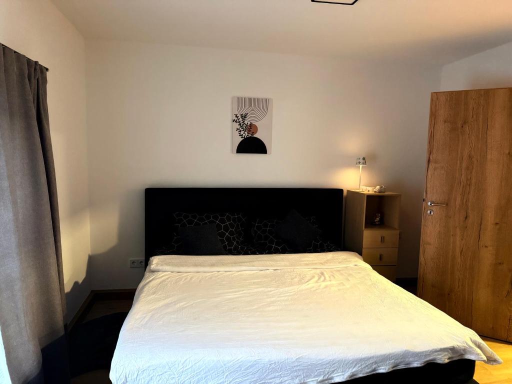 a bedroom with a white bed with a black headboard at BM Wohnung in Dillingen an der Saar
