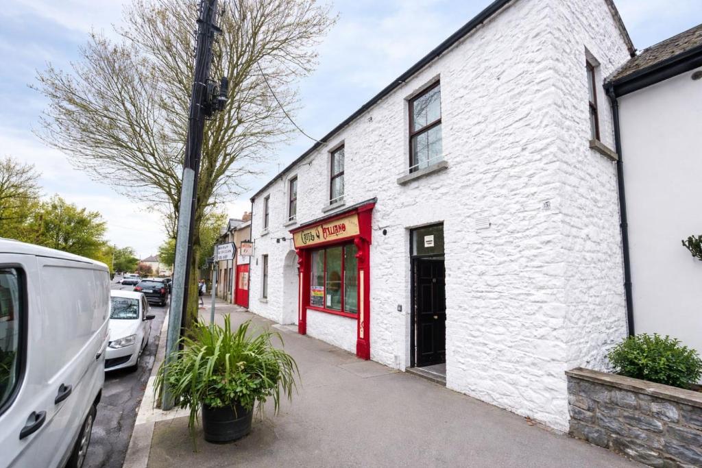 a white building with red doors on a street at The Malting House in Skerries