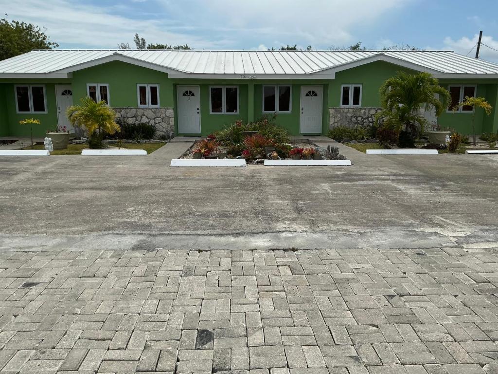 a green house with a brick driveway in front of it at Jubilee Gardens Freeport in Freeport