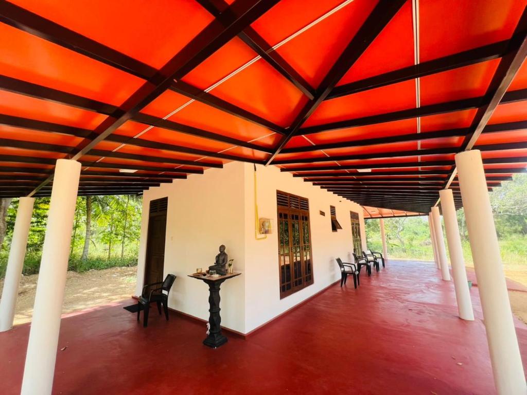 a room with a red ceiling and tables and chairs at Thew Guest Wilpattu in Nekattegama